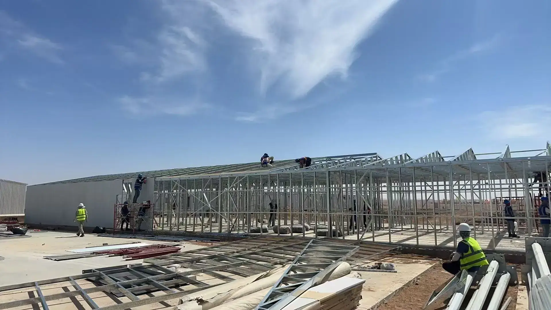Workers installing insulation system on steel structure building